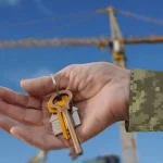 Ветеран тримає ключі від житла на тлі кранів за програмою єОселя