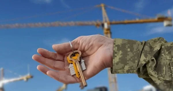 Ветеран тримає ключі від житла на тлі кранів за програмою єОселя