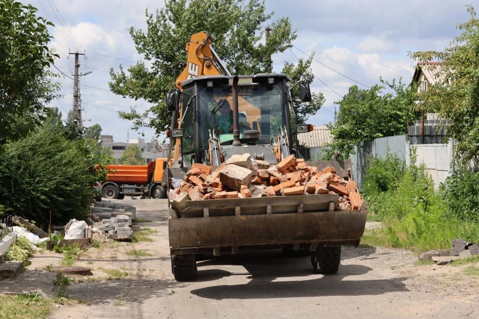 Екскаватор вивозить цеглу під час відновлення Вишневого після обстрілу