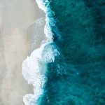 Аерофото піщаного пляжу з бірюзовою водою та білою піною хвиль