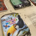 Обгорілі дитячі книжки з попелом на столі після обстрілу складу