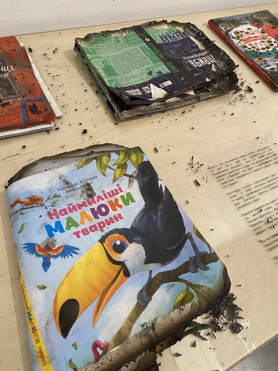 Обгорілі дитячі книжки з попелом на столі після обстрілу складу